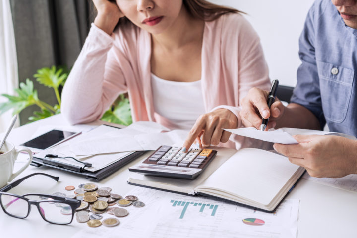 Casal preocupado com o CNPJ inapto, fazendo contas na calculadora