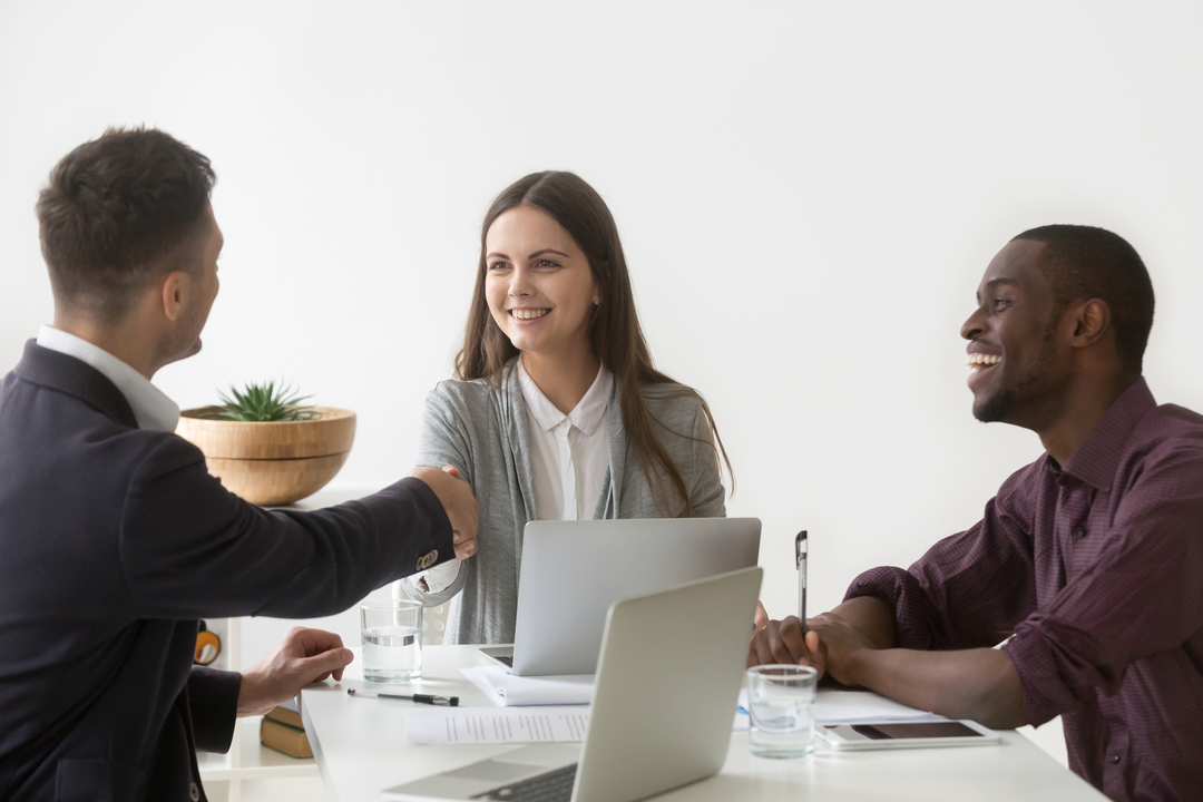 Mulher sorrindo e apertando a mão de um homem formalizando uma sociedade empresária